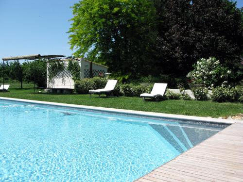 - une piscine avec 2 chaises longues à côté d'une cour dans l'établissement Le Jardin d'Érables St Remy 7 HA Piscine/Clim, à Paluds de Noves