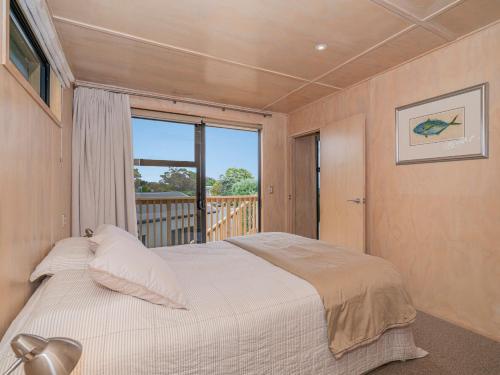 1 dormitorio con 1 cama grande y balcón en All Decked Out - Matarangi Holiday Home, en Matarangi