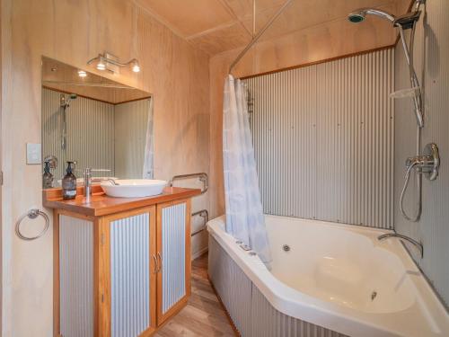 y baño con bañera, lavamanos y bañera. en All Decked Out - Matarangi Holiday Home, en Matarangi