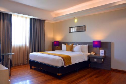 a hotel room with a large bed with two lamps at Truntum Padang in Padang