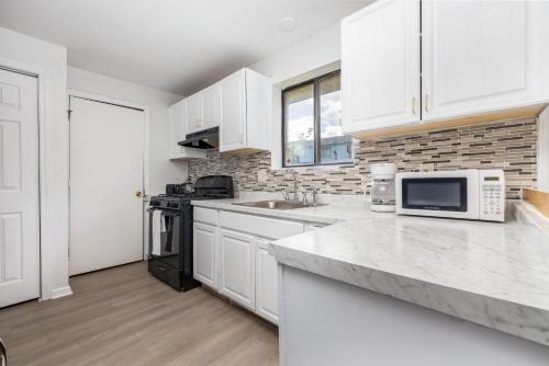 a white kitchen with white cabinets and a microwave at Beautiful 3 bedroom Condo in Hartford! in Hartford