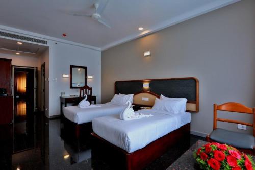 a hotel room with two beds and a television at Lemongrass inn munnar in Anachal
