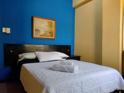 a blue bedroom with a bed with a blue wall at Hotel Alajuela Costa Rica Airport in Alajuela