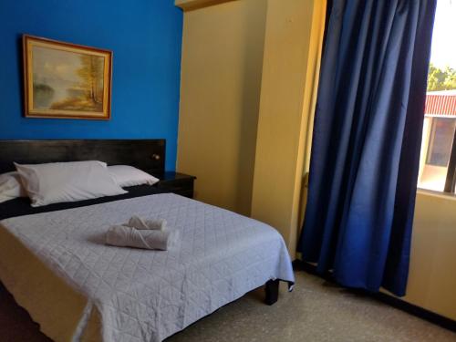 a bedroom with a bed with blue walls and a window at Hotel Alajuela Costa Rica Airport in Alajuela City