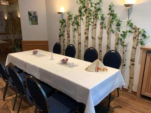 a table in a room with chairs and a fence with plants at Hotel Luther Birke Wittenberg in Lutherstadt Wittenberg