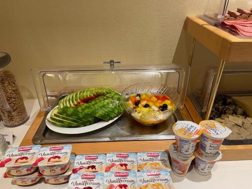 a counter with a plate of vegetables and a bowl of fruit at Hotel Luther Birke Wittenberg in Lutherstadt Wittenberg