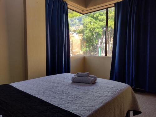 a bedroom with a bed with blue curtains and a window at Hotel Alajuela Costa Rica Airport in Alajuela City