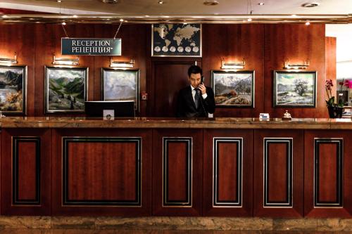un hombre hablando por celular en un bar en Rahat Palace Hotel, en Almaty