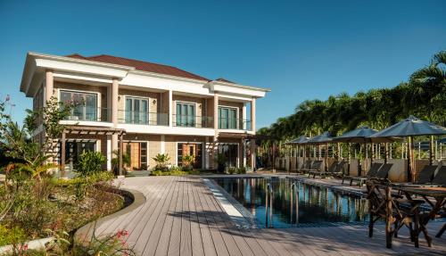 a house with a swimming pool and tables and umbrellas at ISLA HOLIDAY HOME in Anse Royale