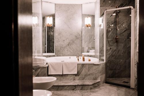 a bathroom with a tub and a shower and a sink at Rahat Palace Hotel in Almaty