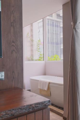 a bathroom with a bath tub and a window at CHERRY BOUTIQUE HOTEL in Ho Chi Minh City