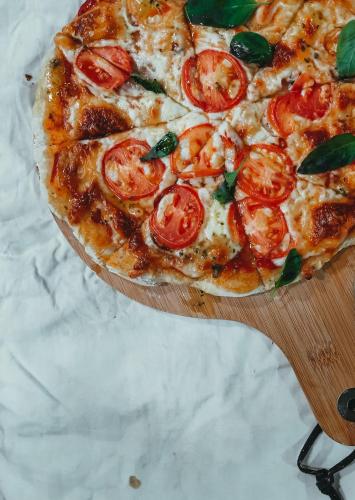 a pizza with tomatoes on a wooden cutting board at Thundi Sea View in Fulidhoo