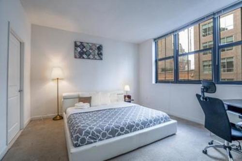 a bedroom with a bed and a desk and windows at Waterfront Baltimore 2BR Furnished Apartment apts in Baltimore