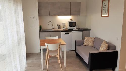 a living room with a table and a couch and a kitchen at Résidence Carouge Appart Hôtel in Brétigny-sur-Orge
