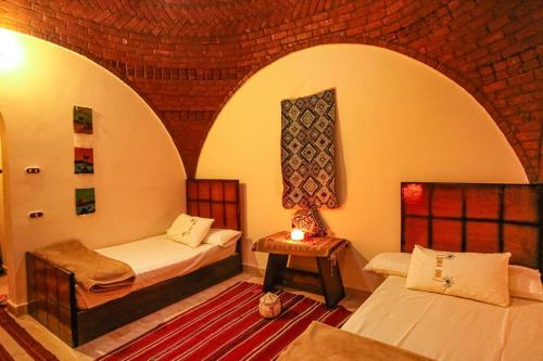 Cette chambre comprend deux lits et une table avec une lampe. dans l'établissement Seliyaa Siwa Inn Hotel, à Siwa