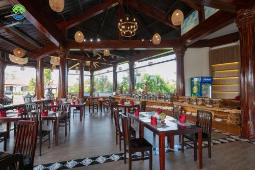 un comedor con mesas, sillas y ventanas en Cantho Eco Resort, en Can Tho