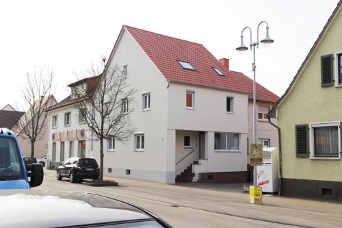 a white house with a red roof on a street at Work & Stay House in Sankt Leon-Rot