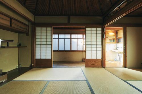 una habitación vacía con puertas y colchonetas en una habitación en Gojo Guest House en Kioto