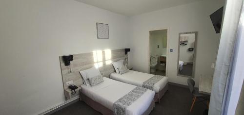 a hotel room with two beds and a mirror at Hôtel L'Alsace in Narbonne