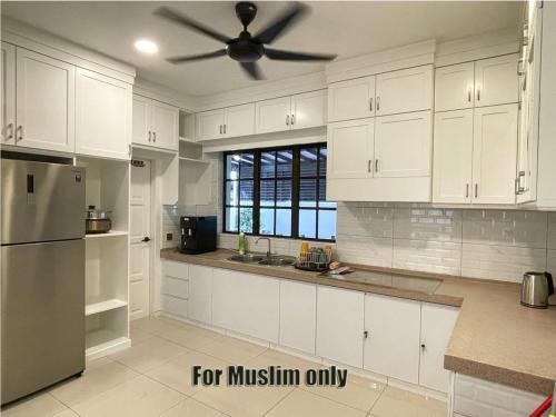 een keuken met witte kasten en een plafondventilator bij Alexis Villa in Muar