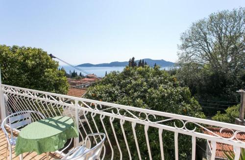 - un balcon blanc avec une table et des chaises vertes dans l'établissement Apartments Anka, à Trsteno