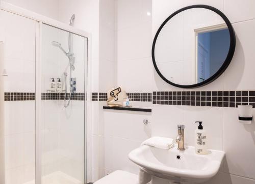 een witte badkamer met een wastafel en een spiegel bij Bob W Tower of London in Londen