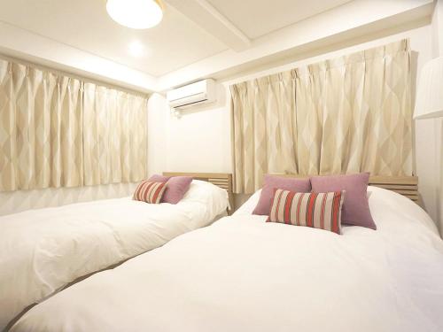 two white beds in a room with curtains at 4 bedrooms cozy house, 5 min JR train to Shinjuku, GRADIA Koenji in Tokyo