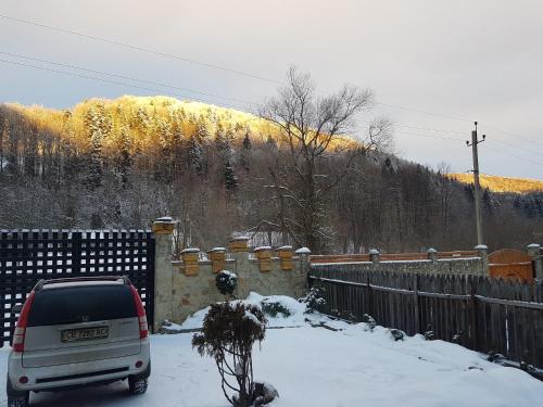 a car parked in front of a fence in the snow at Шале "Тиша" in Migovo