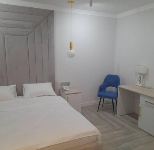 a bedroom with a bed and a blue chair at Kaspi Hotel in Uralsk