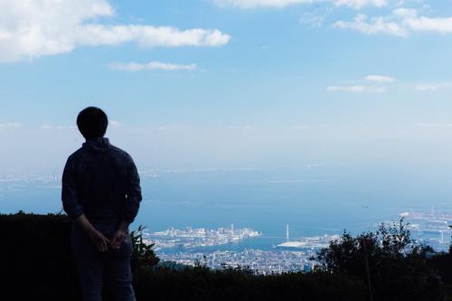 a man standing on top of a hill looking at the city at ROKKONOMAD in Kobe