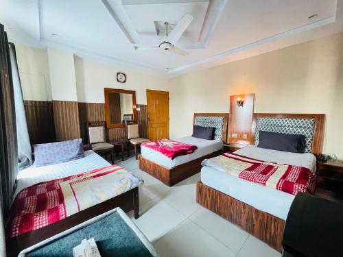 ein Hotelzimmer mit 2 Betten und einem Stuhl in der Unterkunft Plaza Inn Hotel in Rahimyar Khan