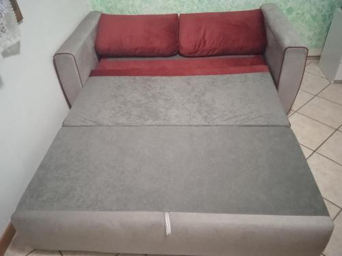 a gray couch with a red pillow on it at Adriella apartments in Bibione