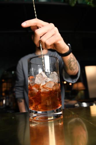 a person is holding a stick in a drink at Loop Hotel Vilnius in Vilnius