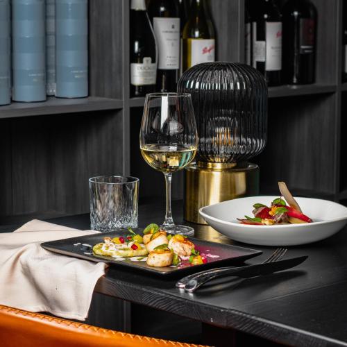 a table with a plate of food and a glass of wine at Loop Hotel Vilnius in Vilnius