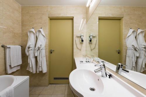 a bathroom with a sink and a mirror and a tub at Congress Hotel in Vilnius