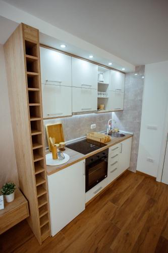 a kitchen with white cabinets and a sink and a stove at Apartman Vesna in Nova Varoš