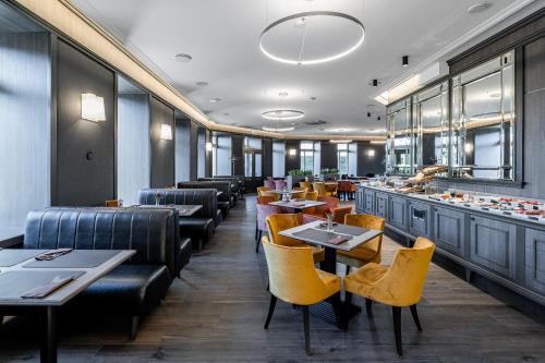 a restaurant with couches and tables and yellow chairs at Congress Hotel in Vilnius