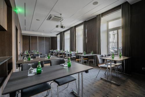 a restaurant with tables and chairs with green bottles on them at Congress Hotel in Vilnius