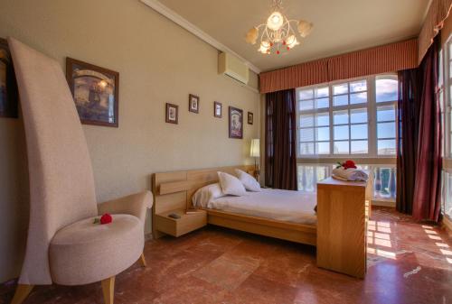 a bedroom with a bed and a chair and a window at Casa Rural Finca Real De Niebla in Niebla