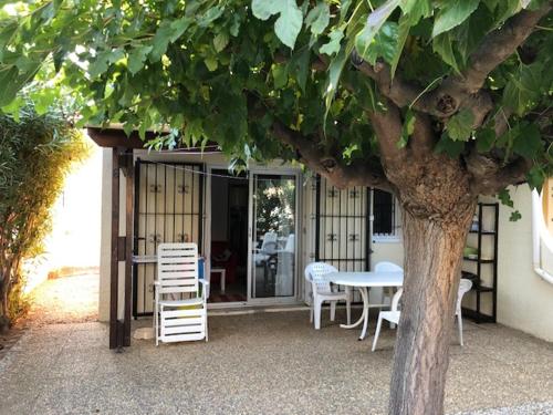 a table and chairs and a table and a tree at Vias Plage - Maison de vacances in Vias