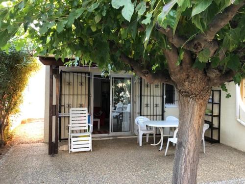 une table, des chaises, une table et un arbre dans l'établissement Vias Plage - Maison de vacances, à Vias