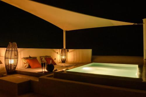 a bathtub in a tent with a couch and lights at Potnia Theron Suites in Akrotiri