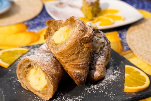 a plate of food with pastries and orange slices at Hotel Murmann in Maratea