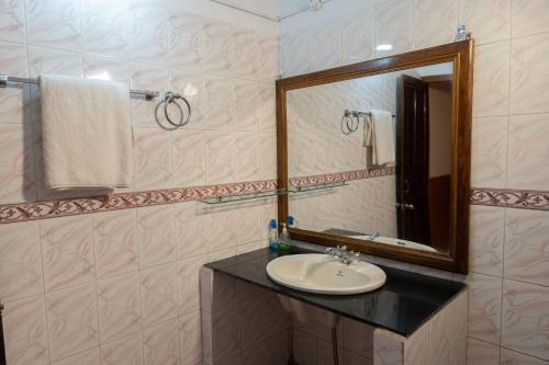 W łazience znajduje się umywalka i lustro. w obiekcie Tarana Cottage by Namastexplorer w mieście Bhowāli