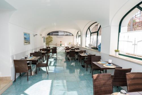 a dining room with tables and chairs and windows at Hotel Murmann in Maratea