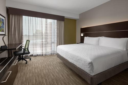 a hotel room with a bed and a desk and a chair at Holiday Inn Express & Suites Woodside LaGuardia Airport in Queens