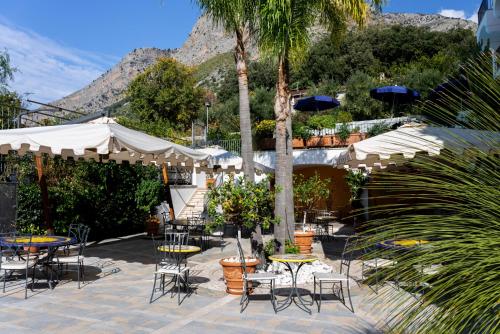 a patio with tables and chairs and palm trees at Hotel Murmann in Maratea