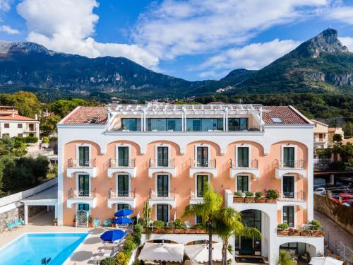 a building with a pool and mountains in the background at Hotel Murmann in Maratea