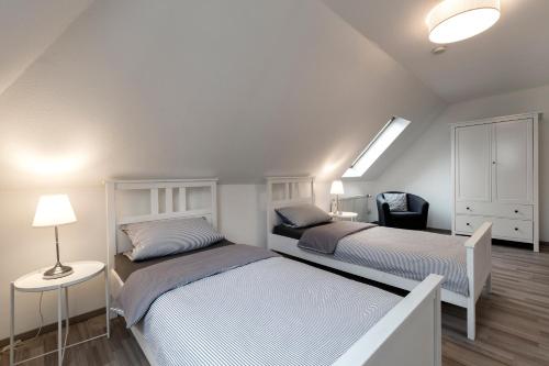 a bedroom with two beds and a lamp and a chair at Arkadia-Home-Hamburg-Airport-Apartment in Hamburg