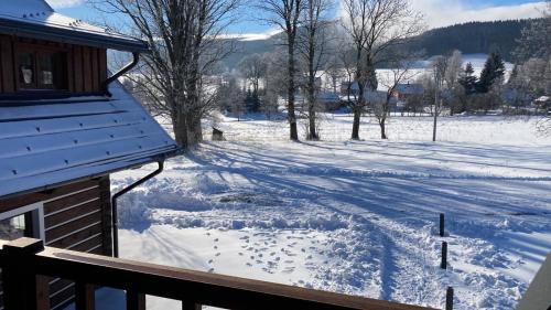 a snow covered yard next to a house at Apartmány U Fibichů in Orlické Záhoří 
